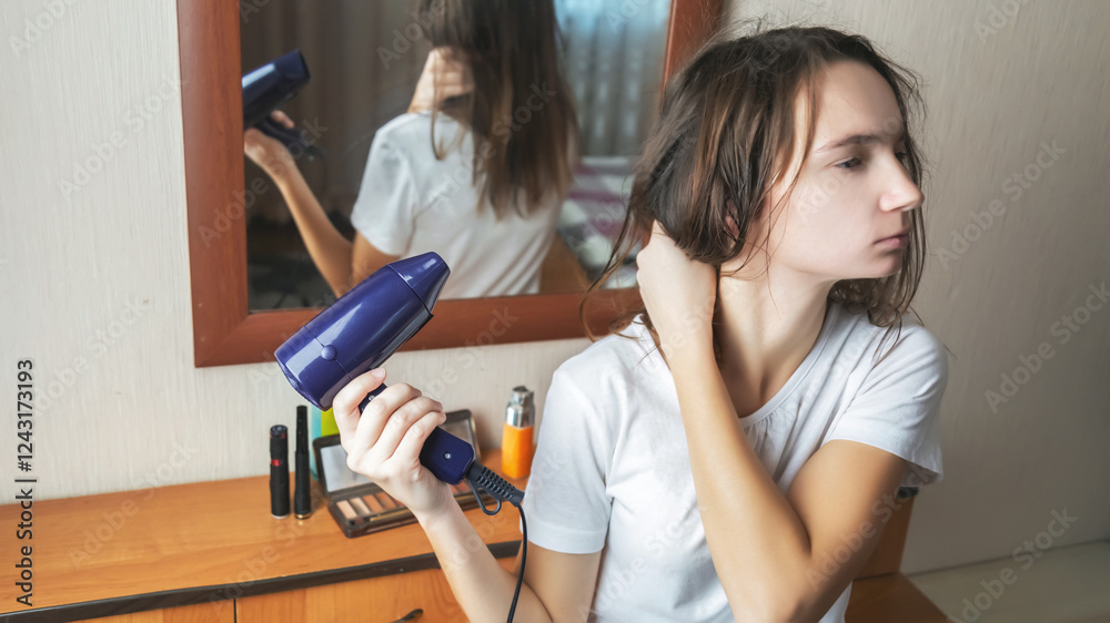 Young woman using a blow dryer and drying her hair in bedroom at home Young woman using a blow dryer and drying her hair in bedroom at home