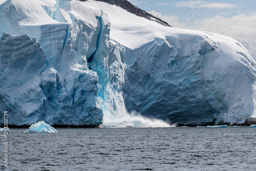 Telephoto of a giant chunk of ice calving off an ice sheet. Graham Passage, near Charlotte Bay, on the Antarctic Peninsula