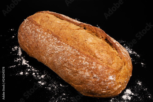 Rustic homemade bread with a crispy golden crust, set against a black background with scattered white mica. A fresh, delicious loaf ready to enjoy.