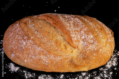 A close-up of craft bread on a black background with white mica scattered around it, delicious fresh bread with a crispy crust, golden brown homemade bread.