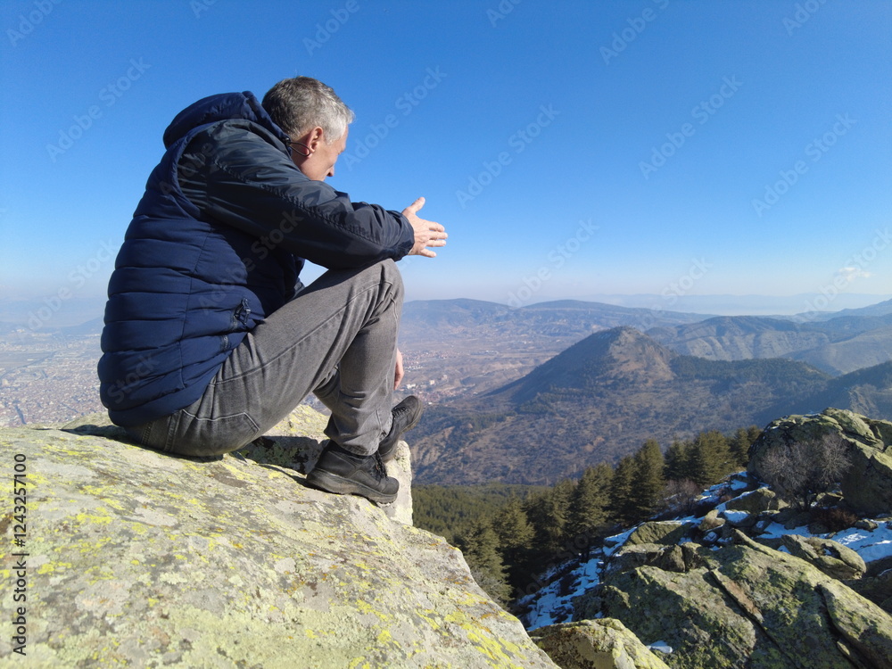 A tourist rests on a mountain peak looking at the beautiful scenery. A tourist rests on a mountain peak looking at the beautiful scenery.