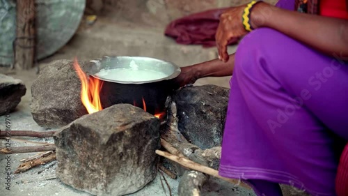 African woman setting a fire to cook milk