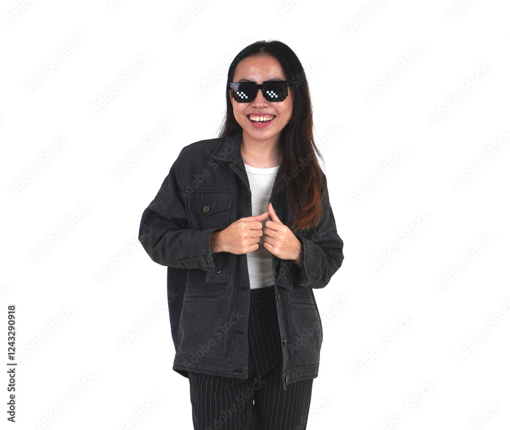 Laughing asian young woman wearing pixel bit styled sunglasses, black denim jacket, and black pants with hands holding the jacket isolated on horizontal white background. Laughing asian young woman wearing pixel bit styled sunglasses, black denim jacket, and black pants with hands holding the jacket isolated on horizontal white background.