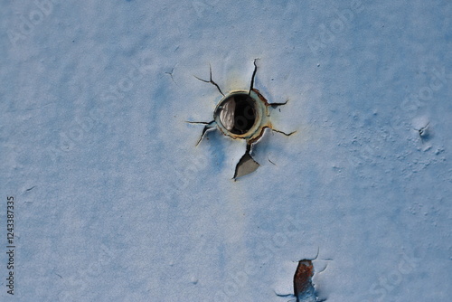 a hole resembling a bullet hole in faded blue metal paint photo