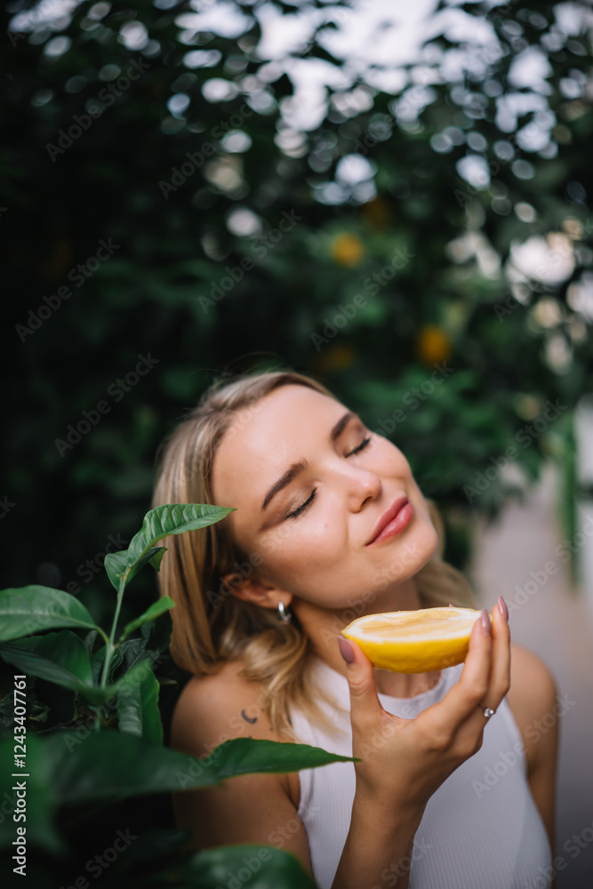 Outdoor portrait of beautiful young woman holding halved lemon fruit Outdoor portrait of beautiful young woman holding halved lemon fruit