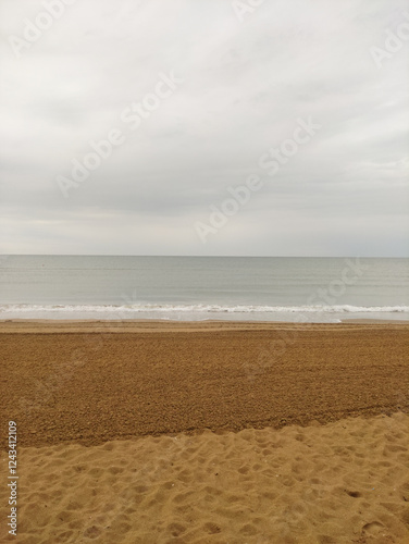 Fototapeta Naklejka Na Ścianę i Meble -  Groomed sand and gentle waves, cloudy beach in bibione, italy, creating a peaceful atmosphere