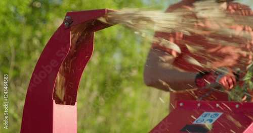 Garden worker using wood chipper shredder machine for making mulch