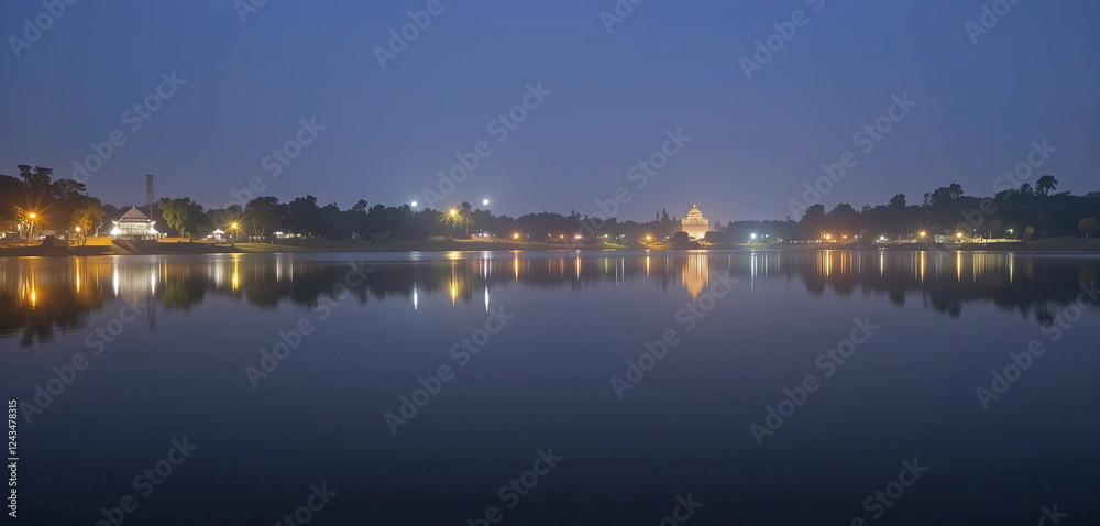 A dreamy night view of Dharwad, where Unkal Lake mirrors the glowing city lights. The still waters create a perfect reflection of the surrounding trees and distant illuminated temples. A dreamy night view of Dharwad, where Unkal Lake mirrors the glowing city lights. The still waters create a perfect reflection of the surrounding trees and distant illuminated temples.