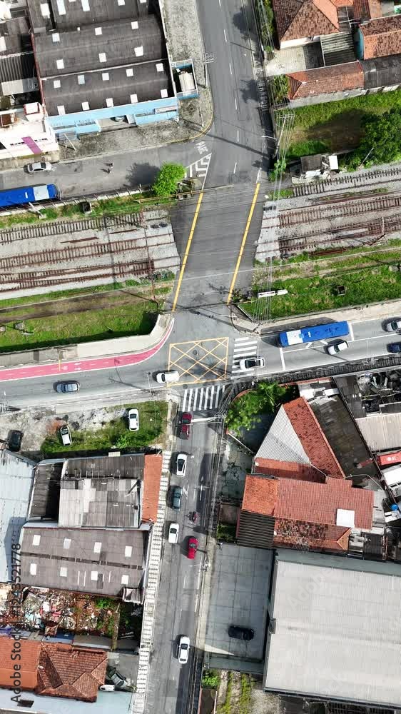 Vídeo vertical capturando a passagem de um trem na cidade de Mogi das Cruzes, São Paulo, enquanto carros aguardam no semáforo fechado. Cena urbana dinâmica e cotidiana