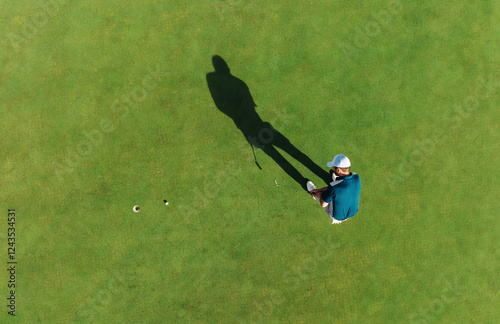 Aerial shot of a man taking a golf action shot and putting on the green