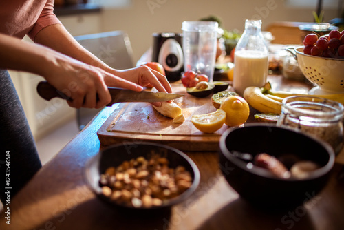 Close up of a woman chopping banana for a smoothie with fresh ingredients