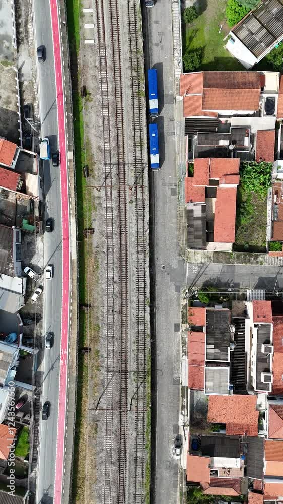 Vídeo 4K mostrando uma visão aérea de veículos circulando em uma avenida movimentada, com a passagem de trem na linha férrea ao fundo, destacando a mobilidade urbana