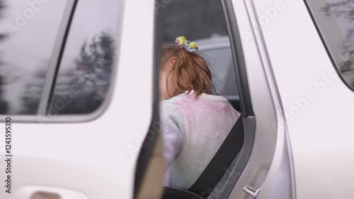 Little girl sitting inside car and closing the door, looking excited and ready for fun road trip, with cheerful expression as she prepares for the journey