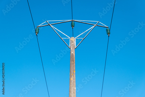 Poste elétrico com linhas de alta tensão contra o céu limpo e azul