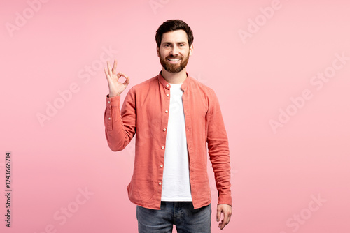 Foto Happy young bearded man showing ok gesture looking at camera against pink backgr