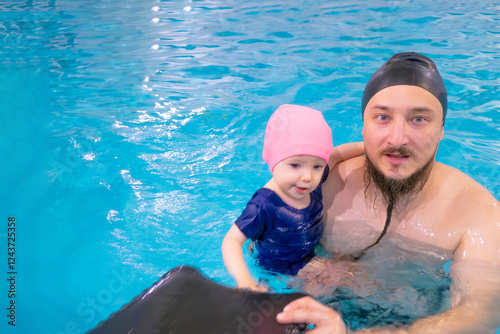 Obraz na płótnie Happy middle-aged father swimming with cute adorable baby in swimming pool. Smiling dad and little child, girl having fun together. Active family spending leisure and time in spa hotel. Concept of w salonie