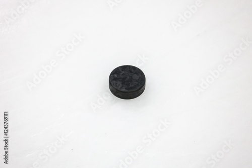 Canvas Print Old Black Single puck laying on ice hockey rink arena.