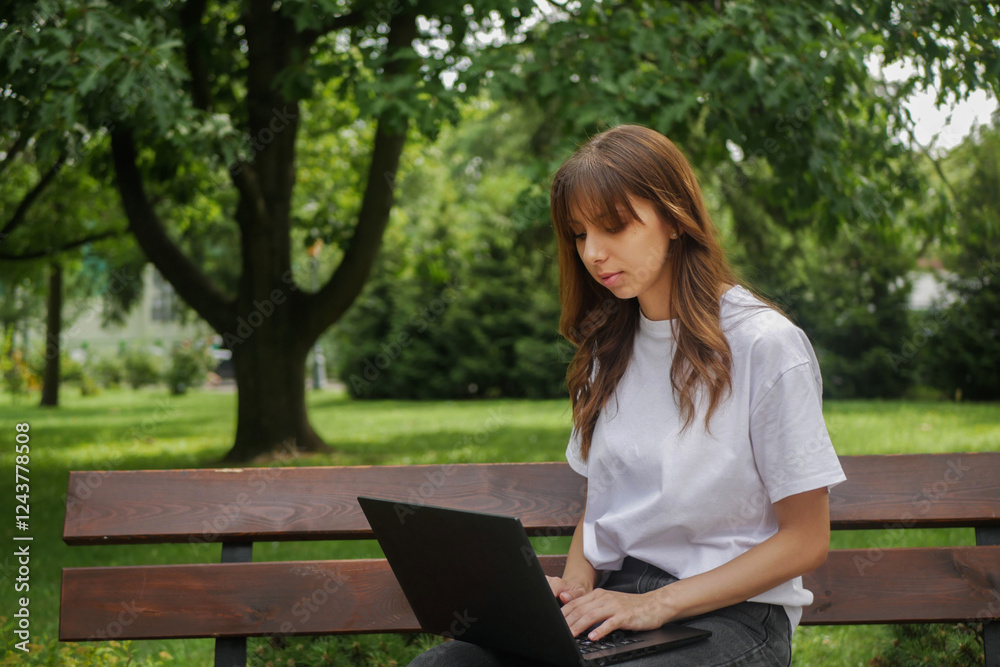 A woman works remotely from a park bench, laptop in hand, embracing the beauty of nature. She blends the flexibility of freelancing with the convenience of online learning in the great outdoors.