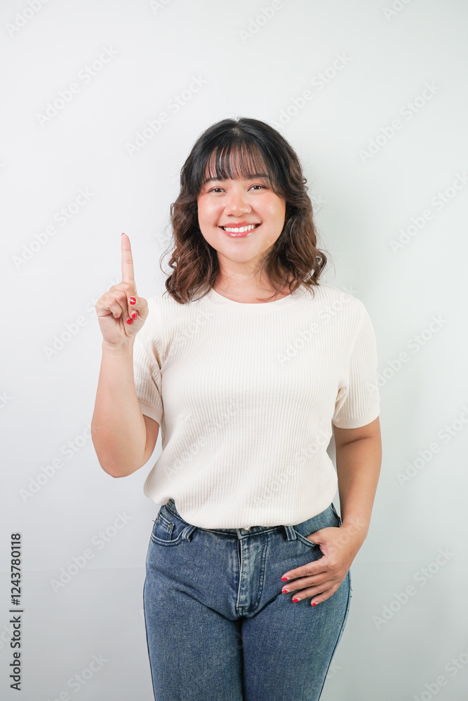 Beautiful young asian woman with wavy hair wearing white shirt is pointing the copy space above her, isolated over white background. Beautiful young asian woman with wavy hair wearing white shirt is pointing the copy space above her, isolated over white background.