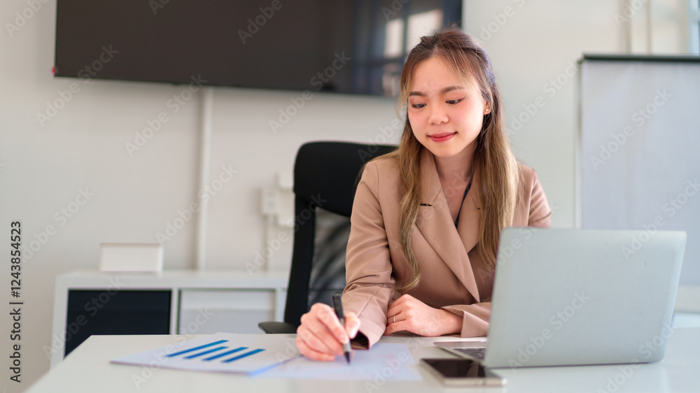 a businesswoman’s hands writing notes while working with documents and a laptop in an office a businesswoman’s hands writing notes while working with documents and a laptop in an office