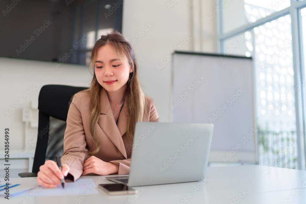 a businesswoman’s hands writing notes while working with documents and a laptop in an office a businesswoman’s hands writing notes while working with documents and a laptop in an office