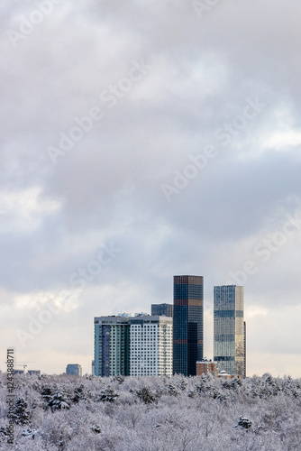 clouds over skyscraper and city park after snowing photo