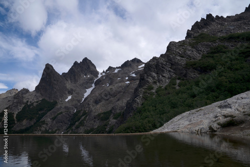 Alpine landscape. Panorama view of Cerro Lopez rocky mountains and the calm lagoon reflecting the environment and sky with dramatic clouds