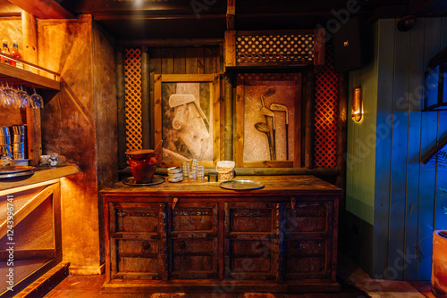 Rustic wooden cabinet with plates, glasses, and pottery, surrounded by golf-themed artwork and warm lighting in a cozy, vintage-style interior. photo