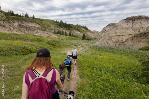 Family hiking along a trail with their dog in the Alberta Badlands on a Summer day