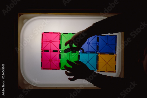 Childâs Hands Creating Patterns on Light Panel photo