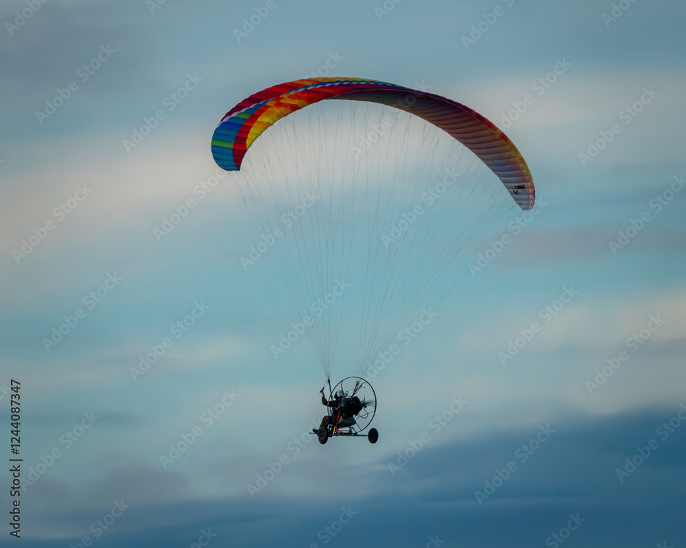 Rainbow colored paraglider among the receding clouds. Rainbow colored paraglider among the receding clouds.