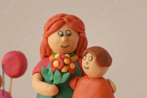 Playful clay figures of mother and child celebrating with flowers photo