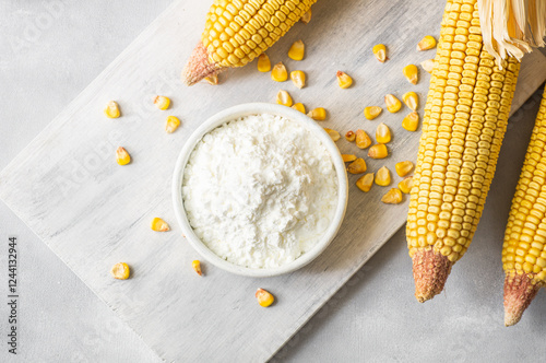 Foto Corn starch in bowl and spoon with dried corn groats, kernels on rustic table