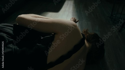 Unrecognisable exhausted young woman dressed in black chemise lying down on floor feeling down because of anxiety disorder