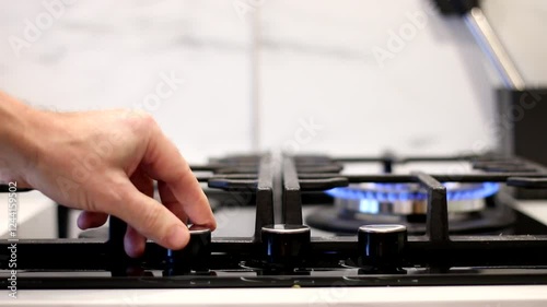 A man's hand lights the gas on a kitchen stove. A cook lights a gas stove to cook food.