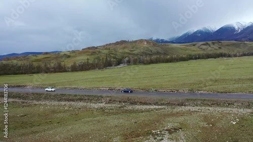 Car is driving along a mountainous road. The quadcopter is following the car.