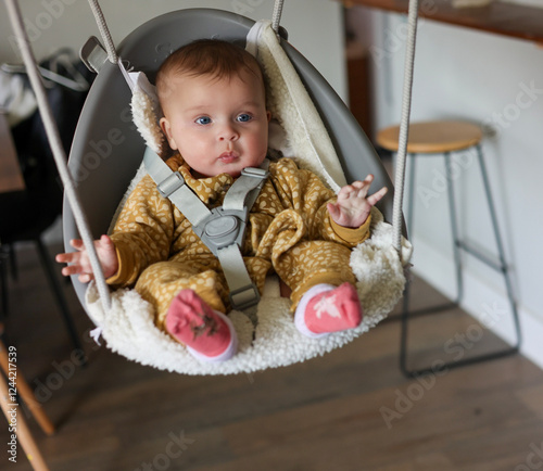 Beautiful Baby on an Indoor Swing with Blue Eyes