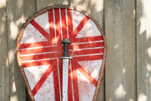 Medieval shield with red patterns and Norman sword in front of rustic wall photo