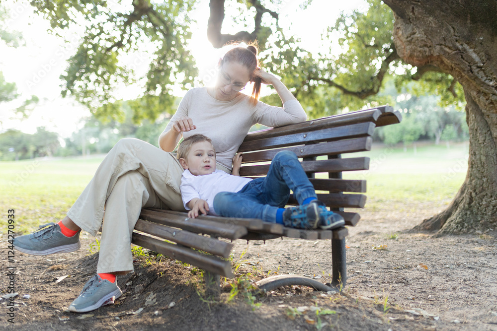 Fototapeta premium Mother and son relaxing on bench in the park