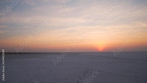 Handheld shot of Sun rising above the salt flats of the Rann of Kutch desert during the morning with orange colored clouds as seen on the way to Dholavira in Kutch, Gujarat, India.  photo