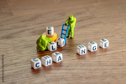 Removing white cubes with letters l and e of the word challenge creating new word change on wooden background with miniature figurines in hazmat biohazard suites