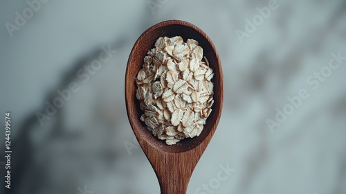Wooden spoon holding rolled oats on marble background photo