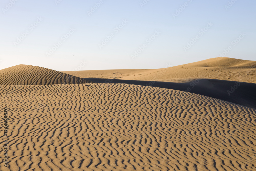 Maspalomas Dunes in Gran Canaria. Textured sand dunes with patterns, shadows, and faint footprints.
