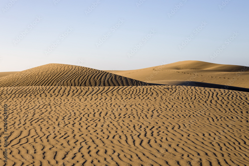 Maspalomas Dunes in Gran Canaria. Textured sand dunes with patterns, shadows, and faint footprints.