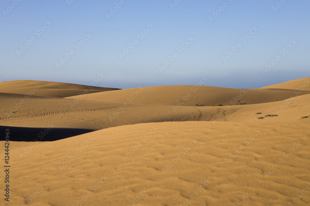 Maspalomas Dunes in Gran Canaria. Textured sand dunes with patterns, shadows, and faint footprints.