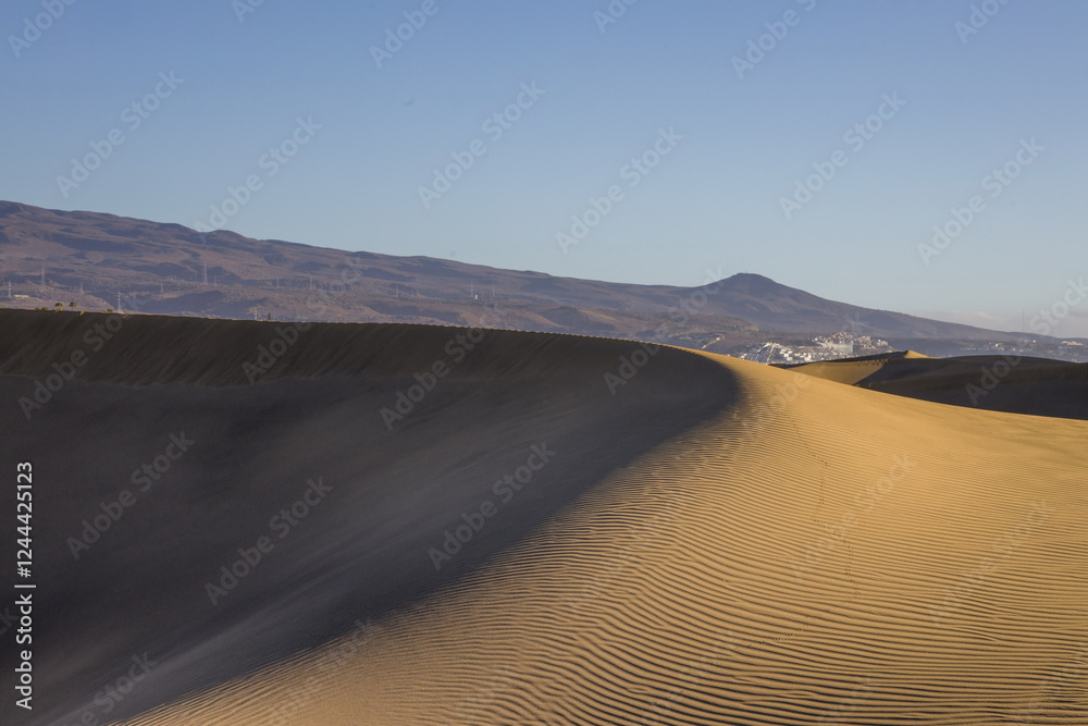 Maspalomas Dunes in Gran Canaria. Textured sand dunes with patterns, shadows, and faint footprints.