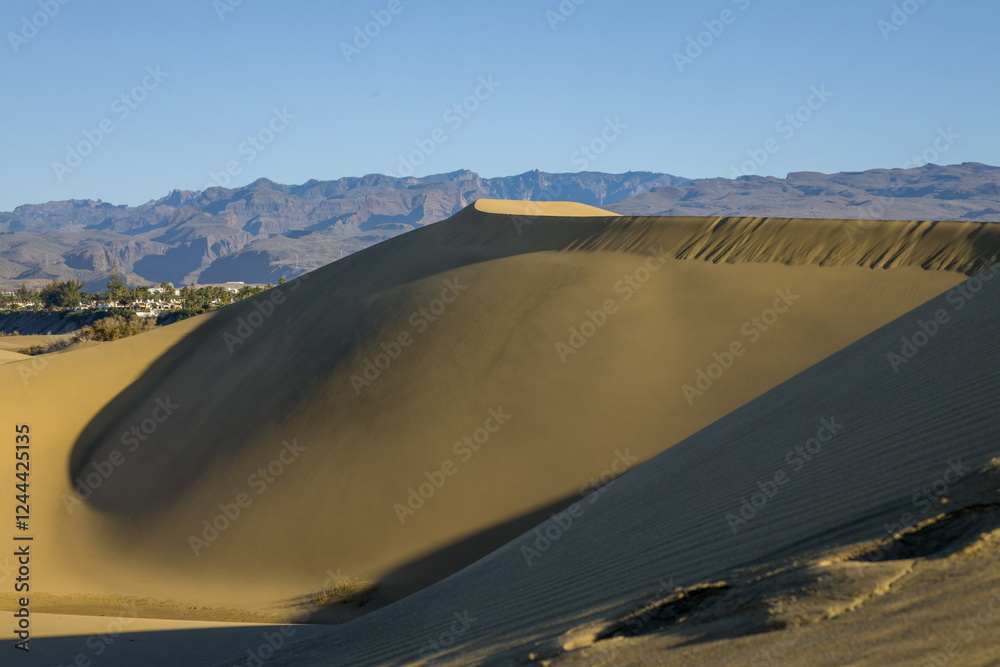 Maspalomas Dunes in Gran Canaria. Textured sand dunes with patterns, shadows, and faint footprints.