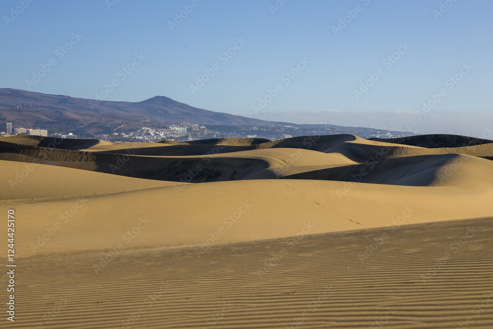 Maspalomas Dunes in Gran Canaria. Textured sand dunes with patterns, shadows, and faint footprints.