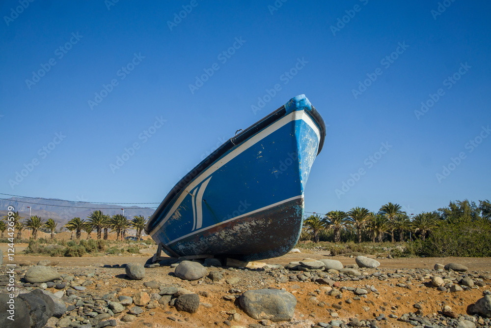 Small, blue boat on a rocky beach.