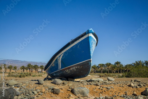 Obraz na płótnie Small, blue boat on a rocky beach. w salonie